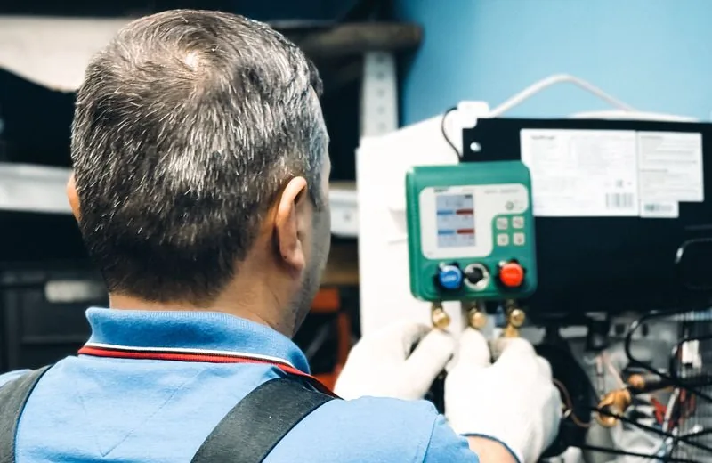 Technieker leest drukmeting en sturing af bij koelinstallatie